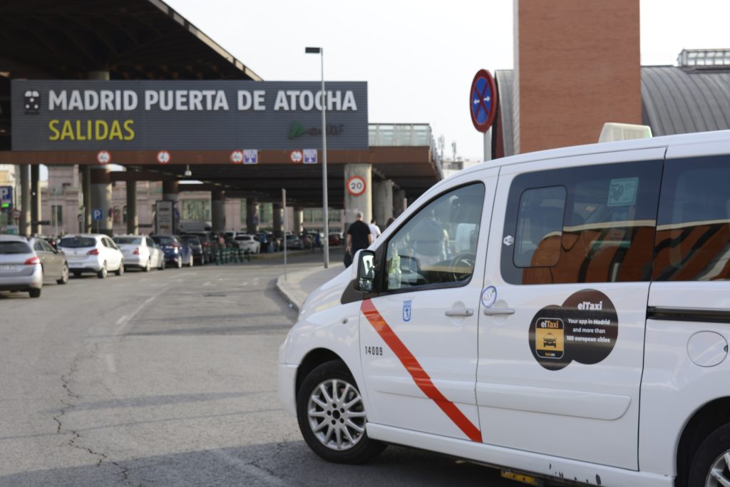 Un taxi oficial de Madrid esperando bajo el rótulo de salidas de la estación de Madrid Puerta de Atocha