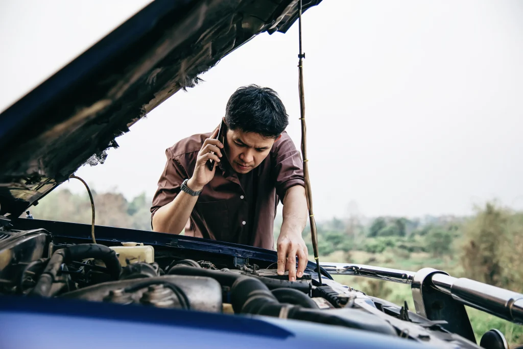 el hombre intenta solucionar un problema de motor de automovil en una carretera local