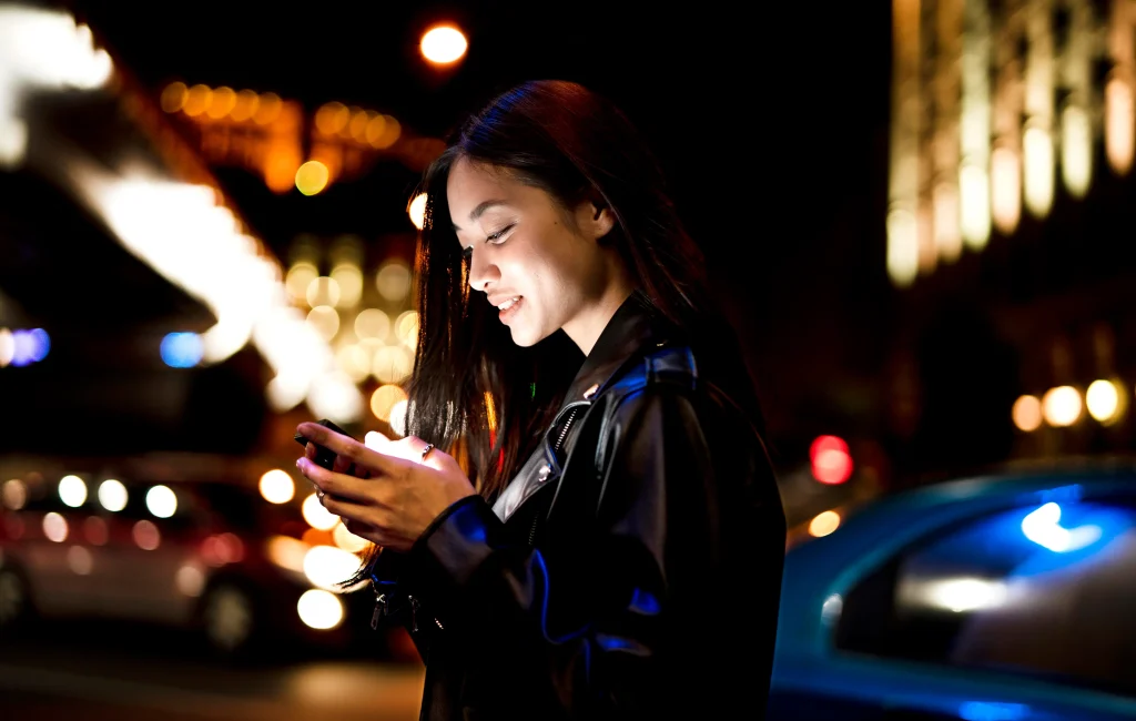 retrato de mujer con smartphone por la noche en las luces de la ciudad