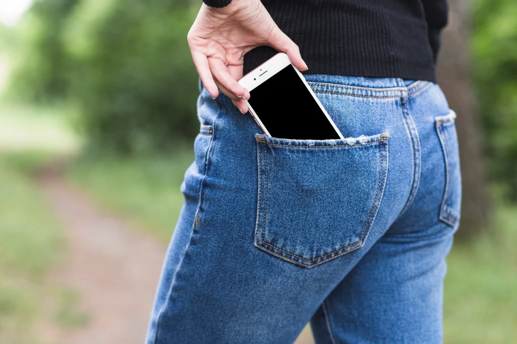 mujer que quita smartphone del bolsillo de los tejanos