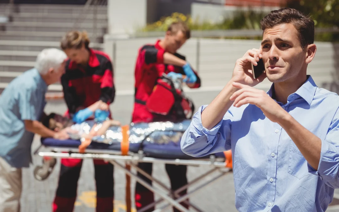 hombre hablando por telefono movil y paramedicos examinando nino herido en segundo plano