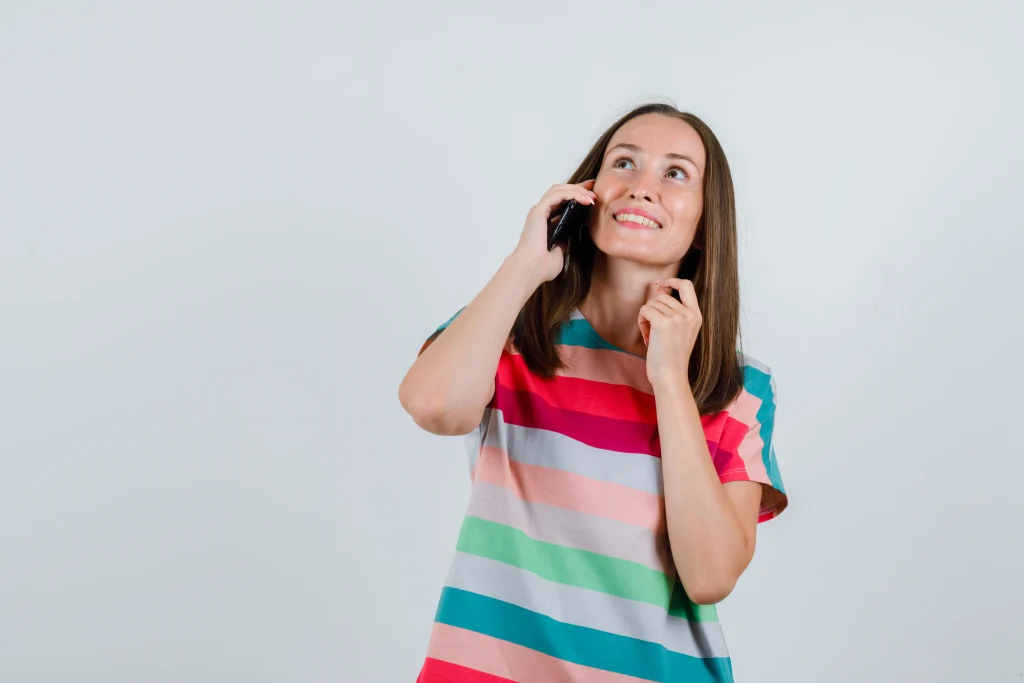 mujer joven hablando por telefono movil en camiseta y mirando feliz vista frontal