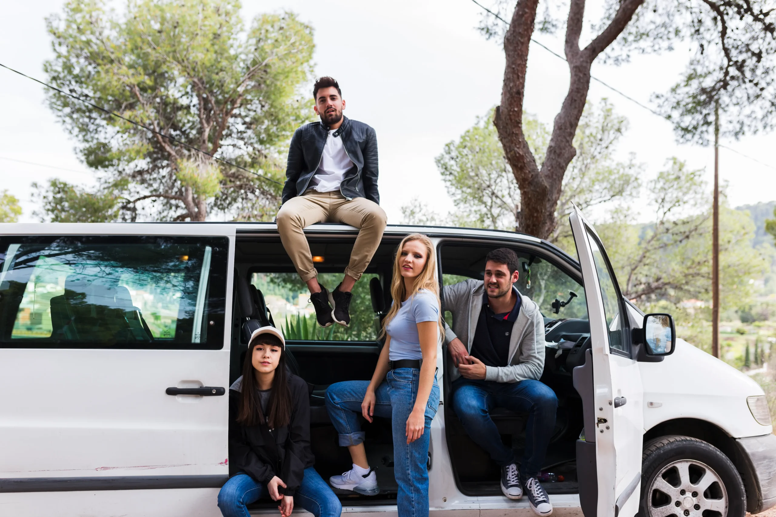 young man sitting top car