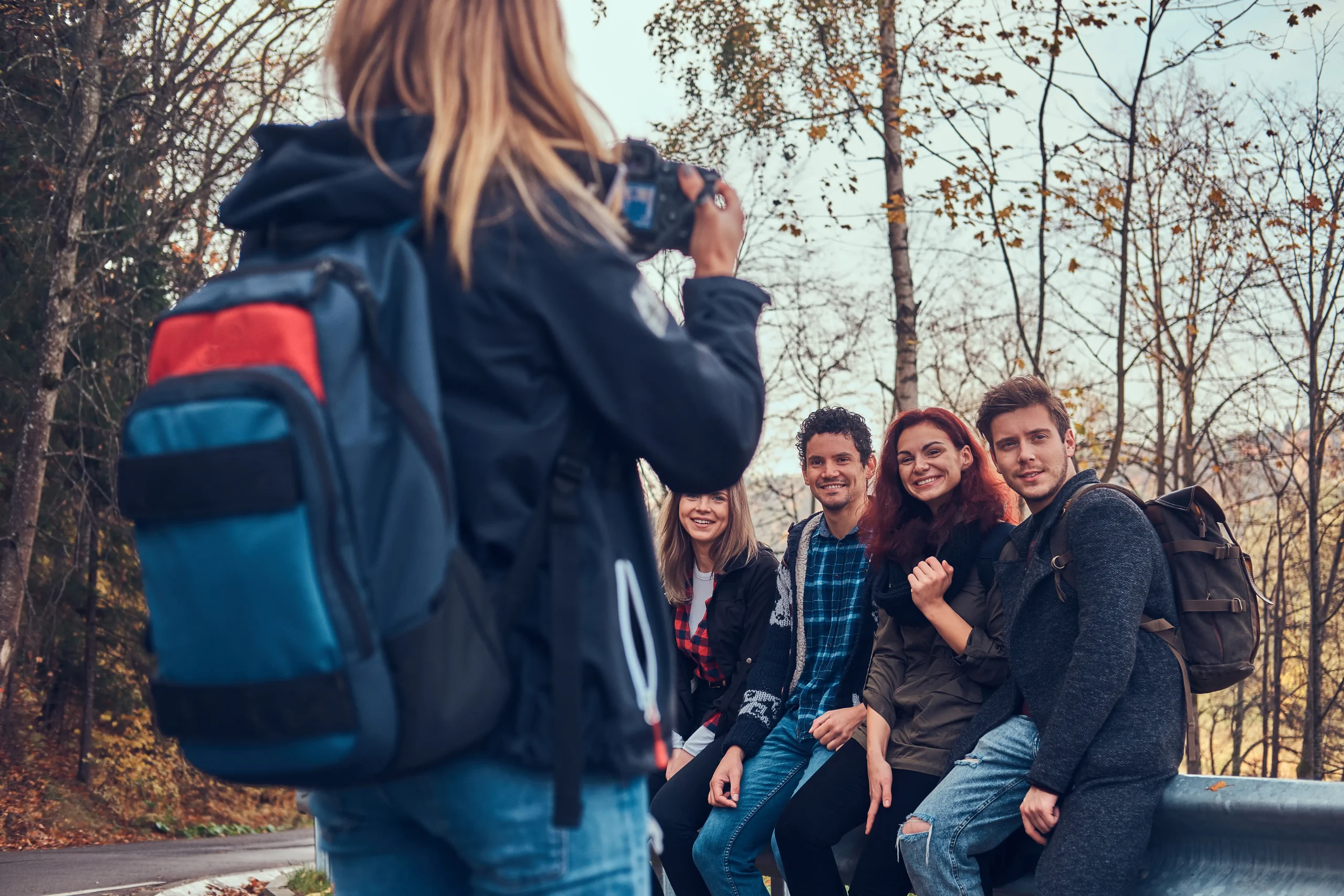 girl taking photo her friends group young friends sitting guardrail near road travel hiking adventure concept