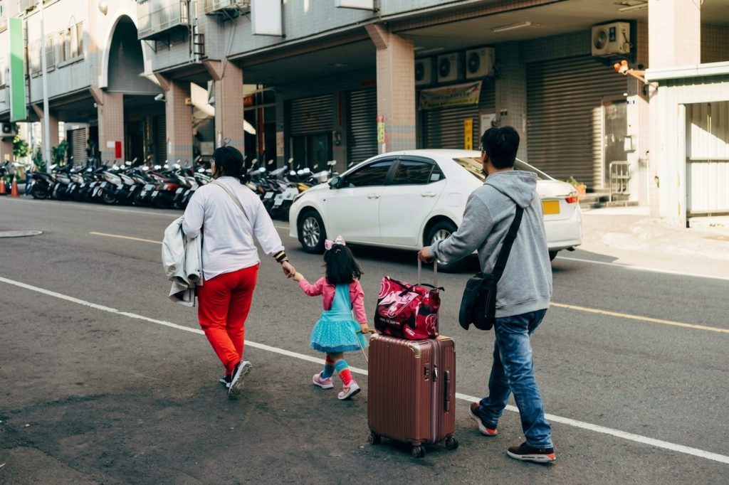 Padres e hija caminando con maleta
